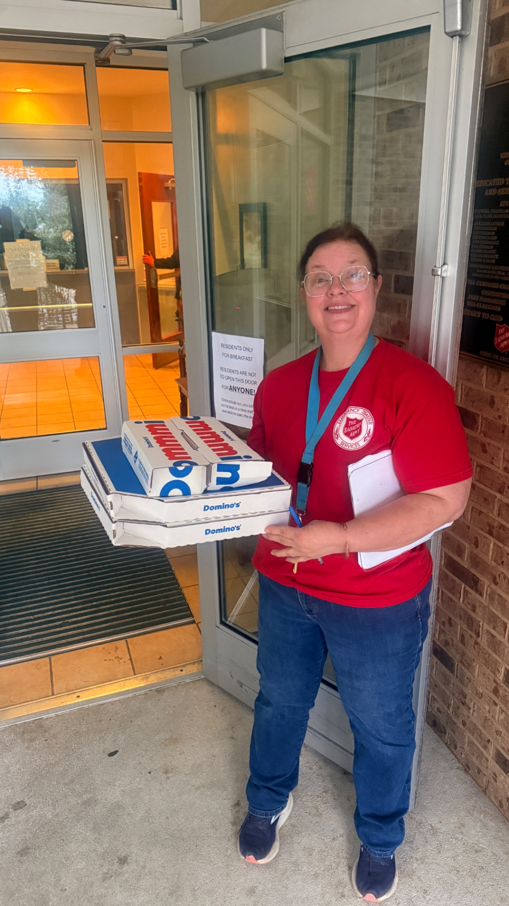 Salvation Army staff member holding pizza boxes at the shelter entrance