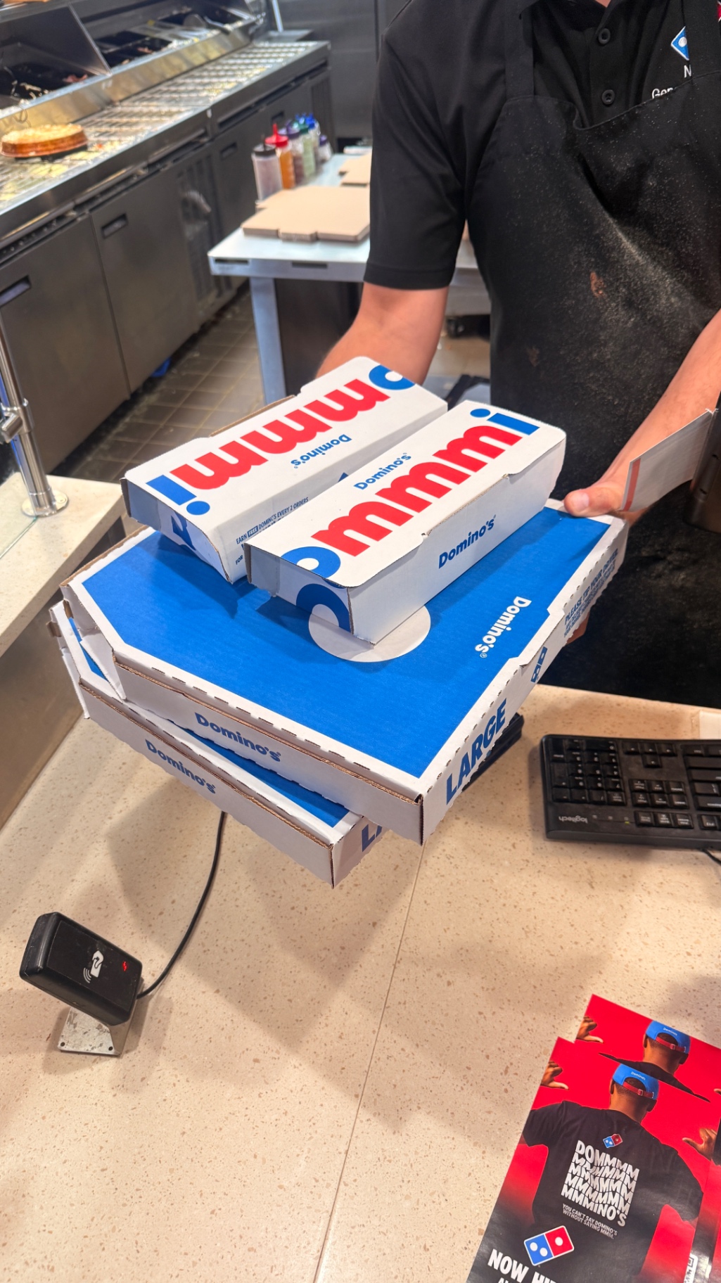 Stack of pizza boxes being picked up at a Papa John's restaurant counter