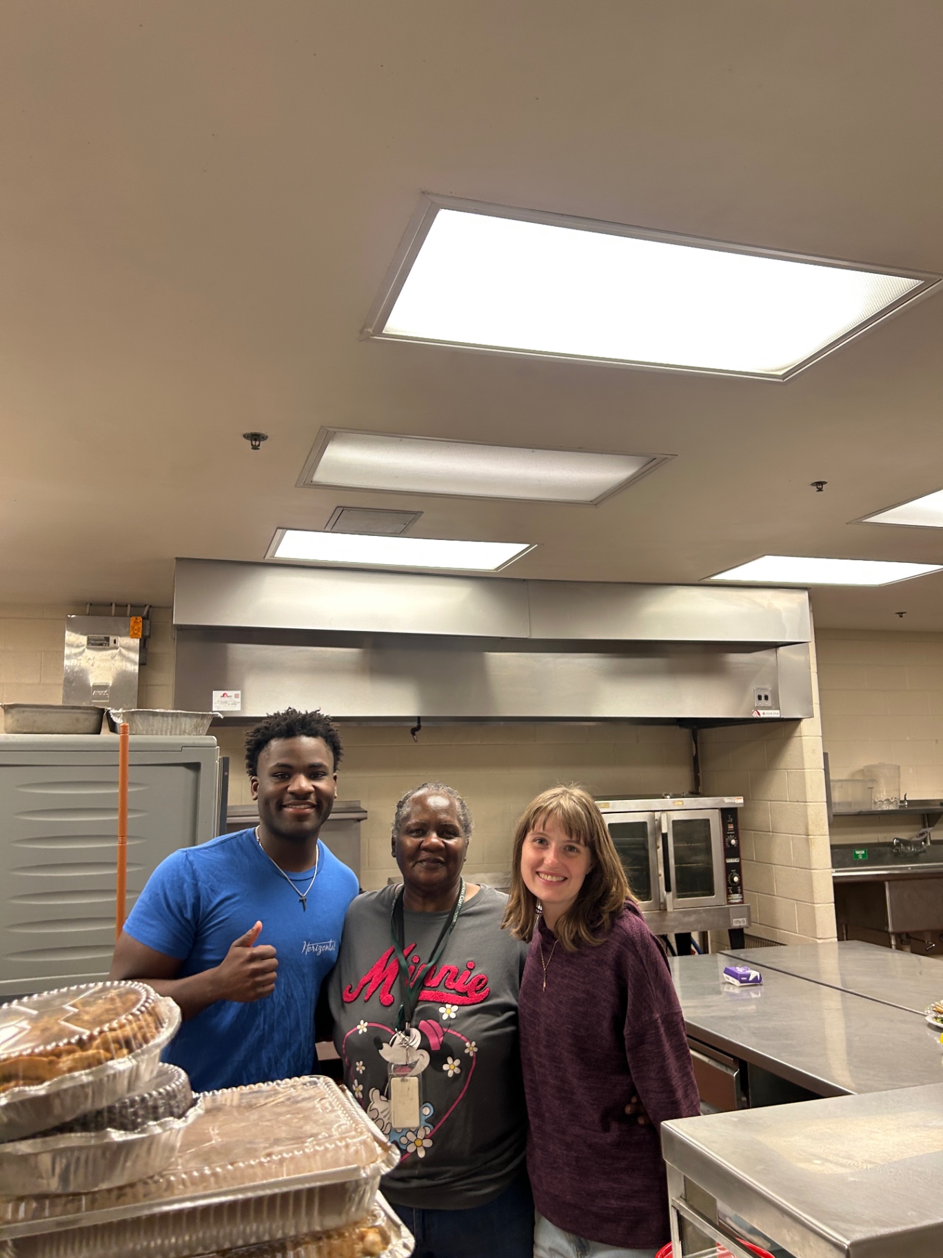 Daniel with two people beside prepared food in a kitchen