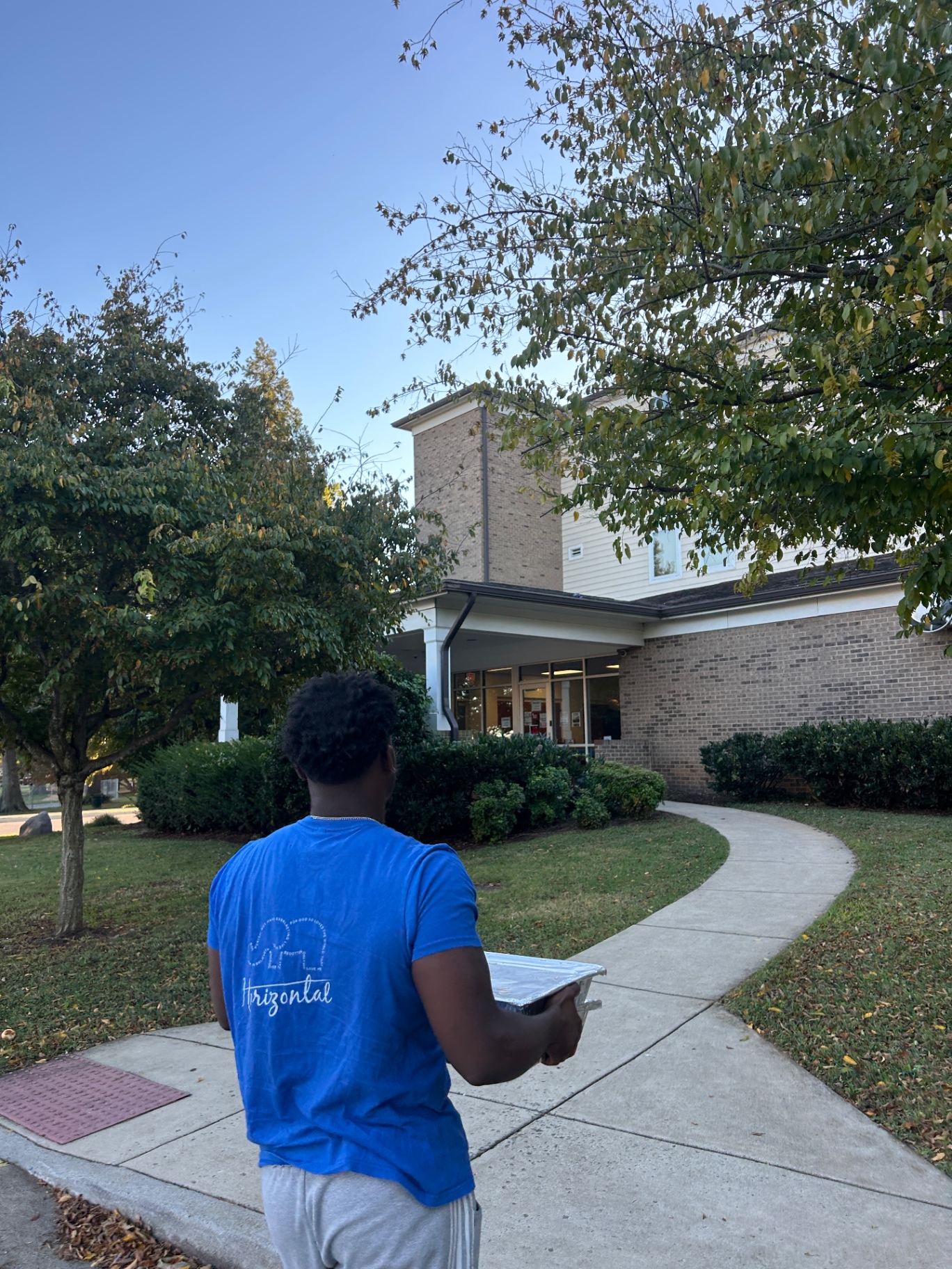 Daniel carrying food toward a building entrance